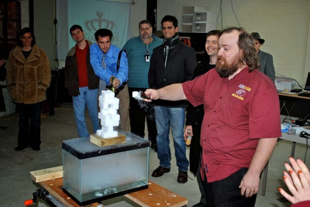 Group watch a man play jenga with tongs and dry ice over an empty aquarium