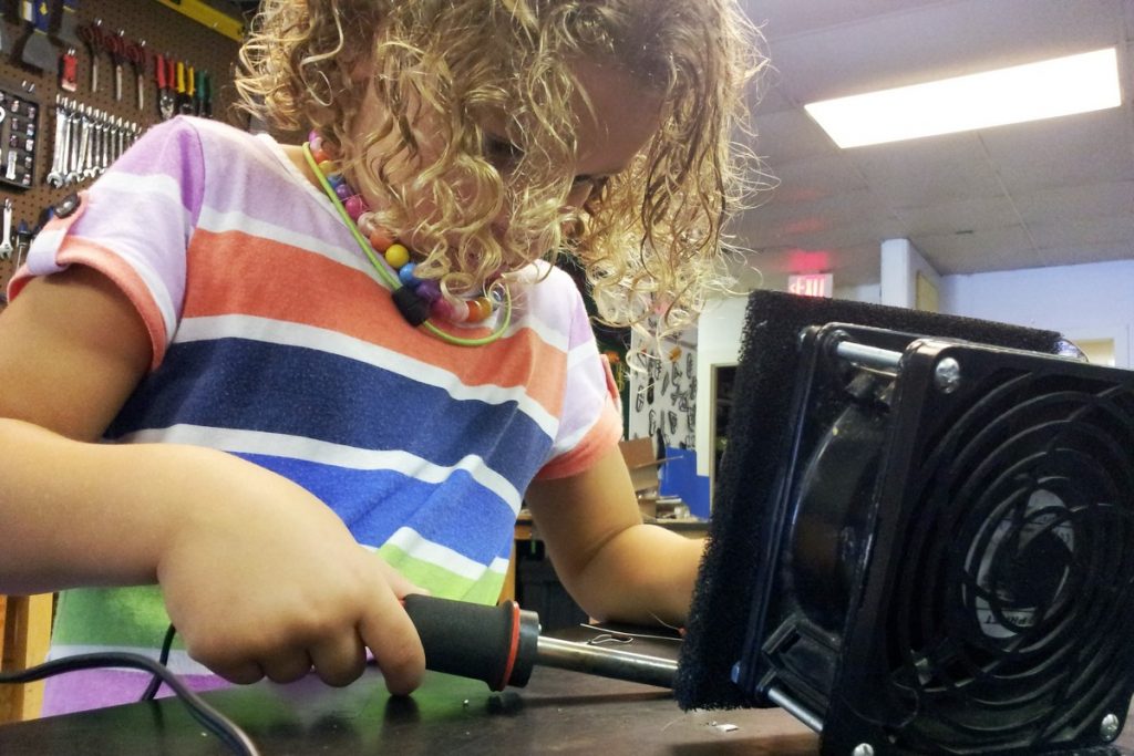 Young girl soldering in a workshop