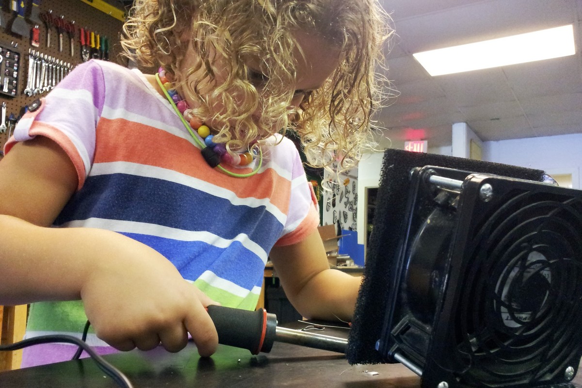 Young girl soldering in a workshop