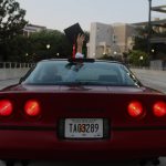 Corvette driving away with driver holding up graduation cap