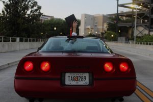 Corvette driving away with driver holding up graduation cap