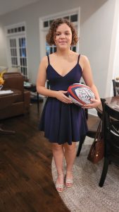 Isabel holding a rugby ball wearing a dress