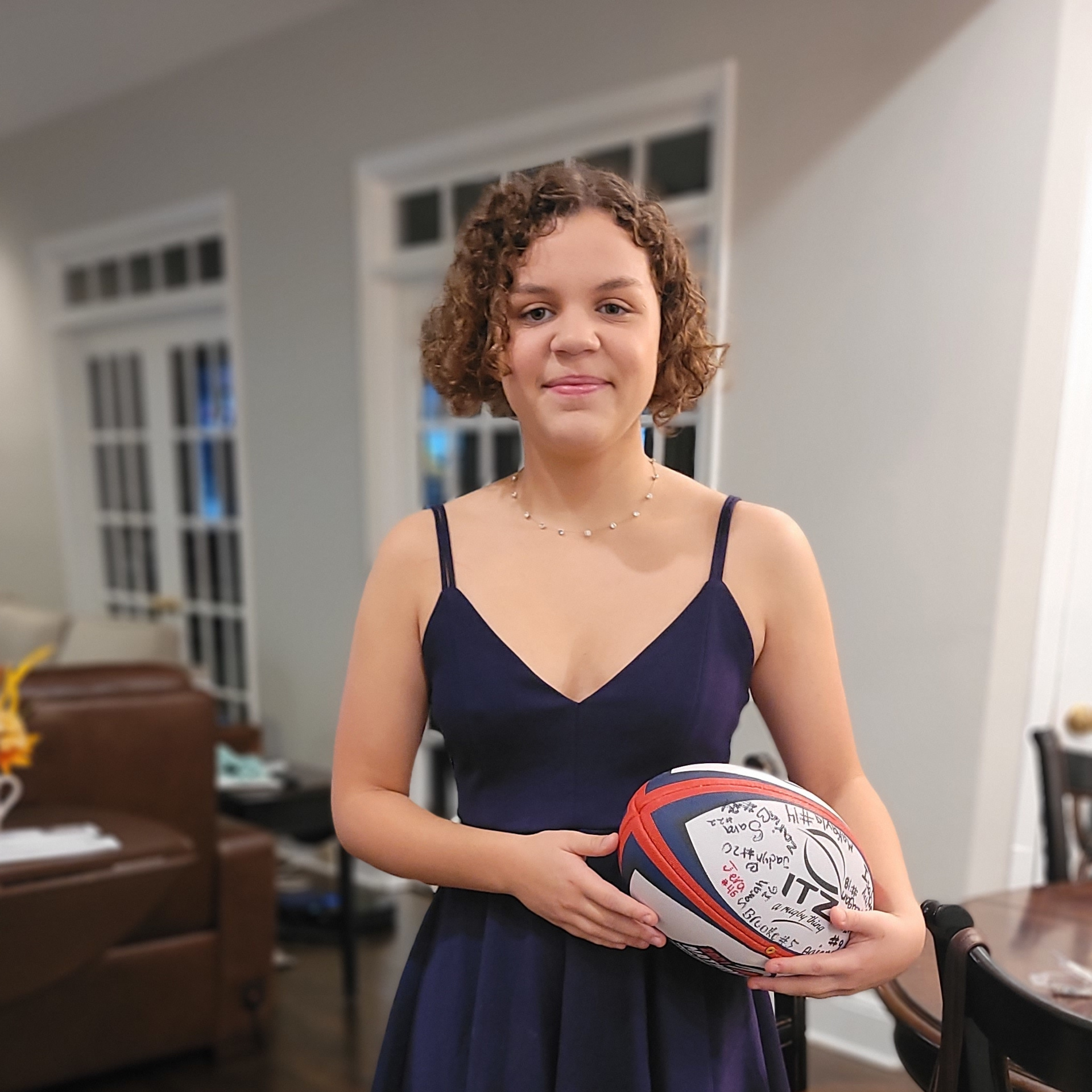 Isabel holding a rugby ball wearing a dress