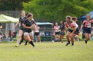 girl running in a match with rugby ball 