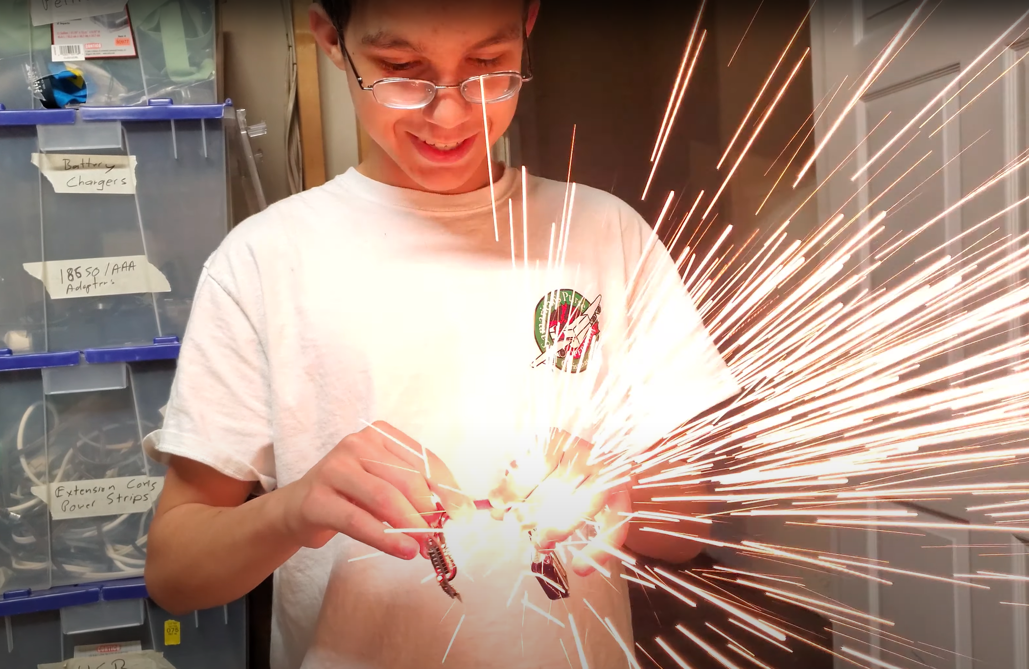 Sparks fly from the hands of a teenager as he connects a lipo battery to some electronics